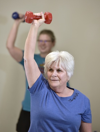 Two people are in a gym lifting up weights